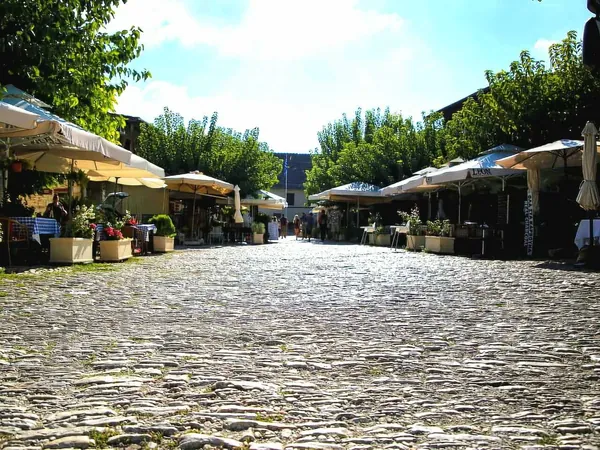 Cobbled main street in Omodos lined with café umbrellas