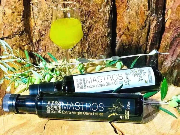 Glass of liqueur and bottles of olive oil among olive branches
