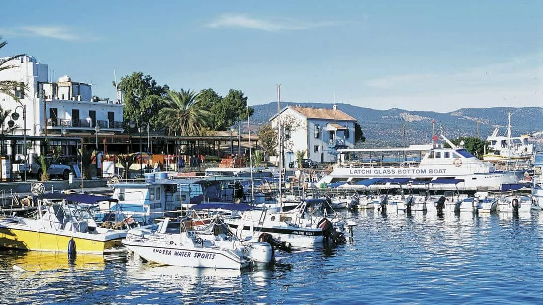 Λιμάνι με εκδρομικά σκάφη και λόφους στο βάθος