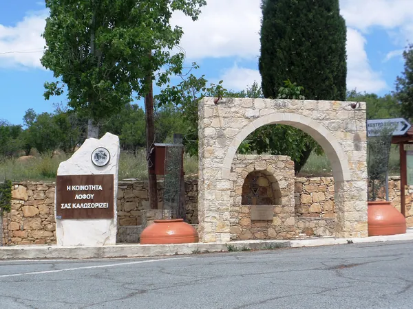 Stone gateway and welcome sign at the entrance to Lofou
